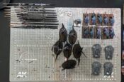 Top-down photo of my cleaned-up paint table featuring only a rack of brushes and three projects: some Slaanesh cavalry, some war hounds of chaos, and a quartet of Kratos tanks for Legions Imperialis.